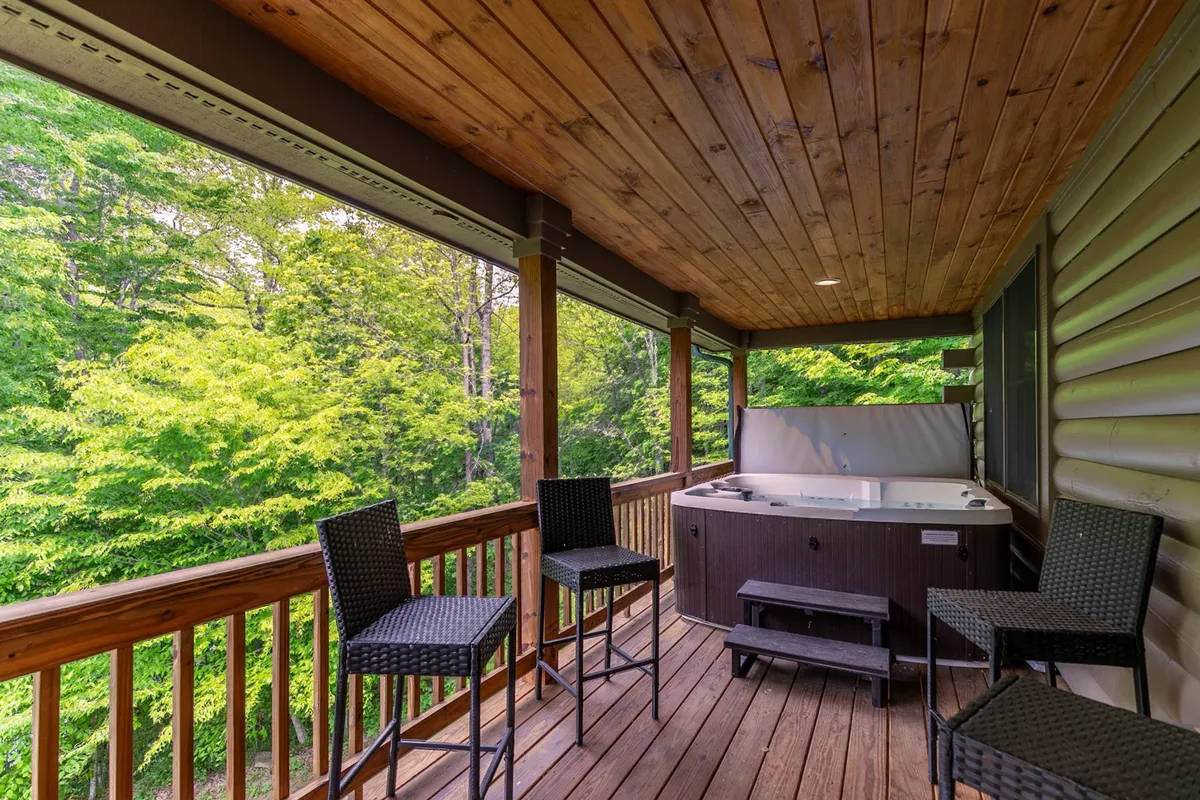 This image showcases a bubbling hot tub on a wooden deck, surrounded by lush greenery and outdoor seating. The natural setting emphasizes relaxation while being immersed in the outdoors, and the deck area hints at social gatherings and easy access to nature.