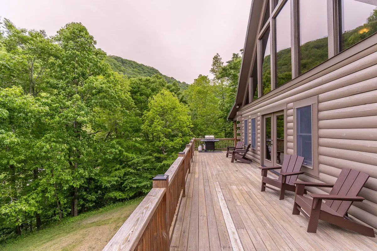 This image showcases a spacious deck surrounded by trees, offering a clear view of the mountains in the background. The seating area invites guests to relax and take in the natural scenery, hinting at the outdoor experiences available nearby. The mood is peaceful, with an emphasis on stargazing and morning coffee with a view.
